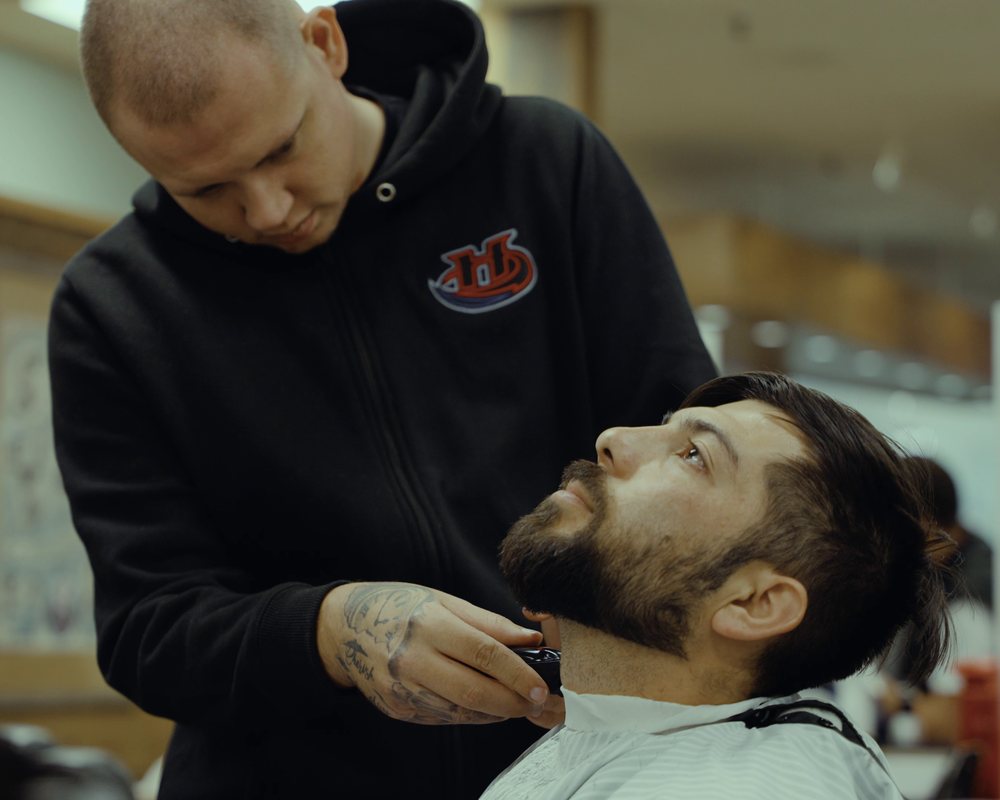 Student barber trimming a client's beard with clippers