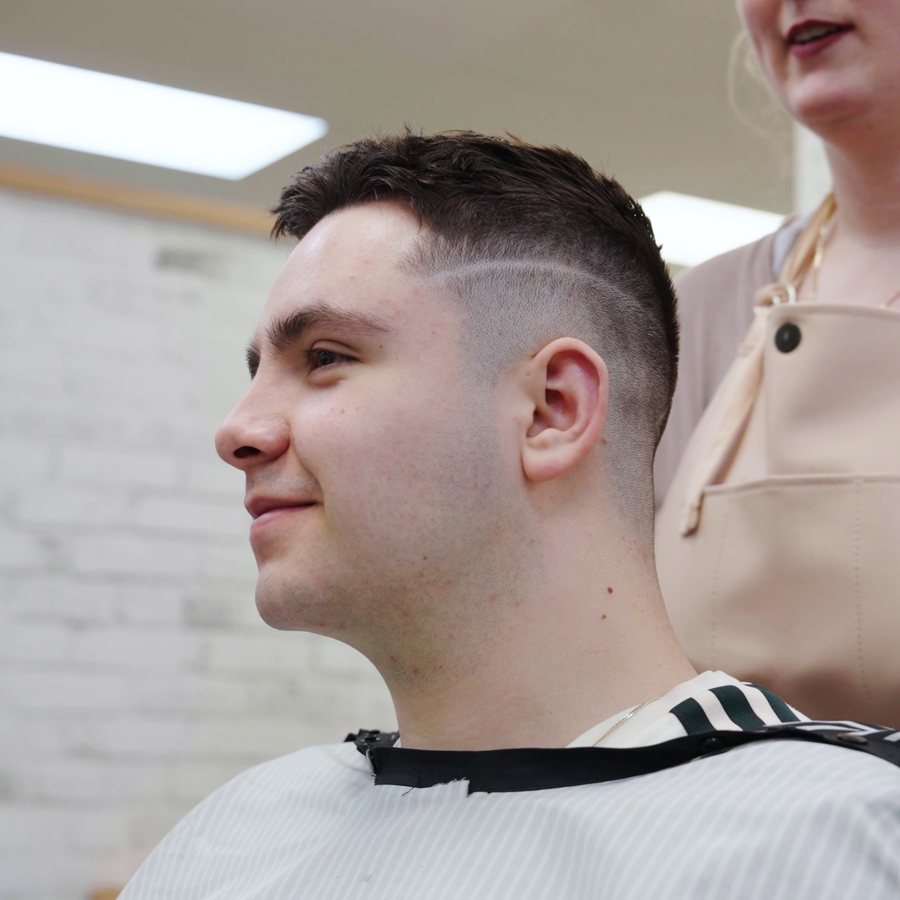 Smiling client showing off a fresh skin fade with a hard part