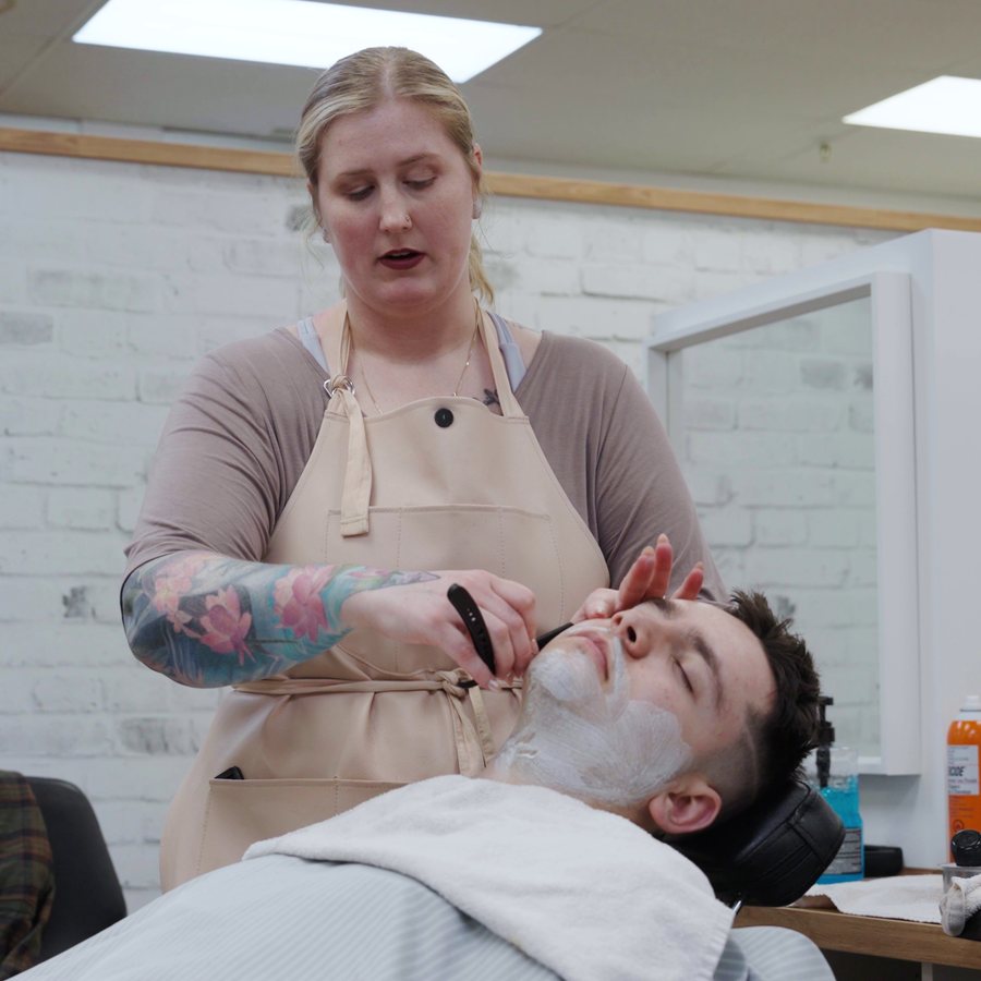 Student barber giving a client a straight-razor shave